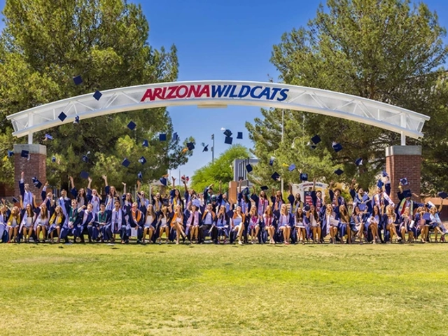 Several college students throw their caps into the air under an archway with the words Arizona Wildcats on it.