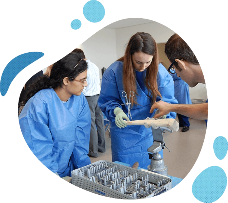 People in blue clothes pointing at a medical training device